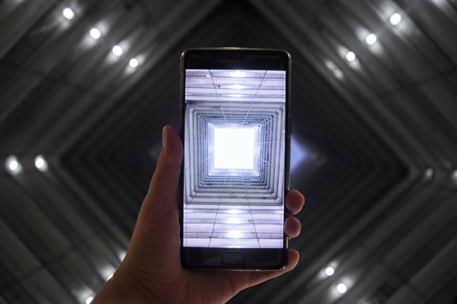 Pantalla de smartphone mostrando un edificio moderno iluminado simétricamente, simbolizando tecnología